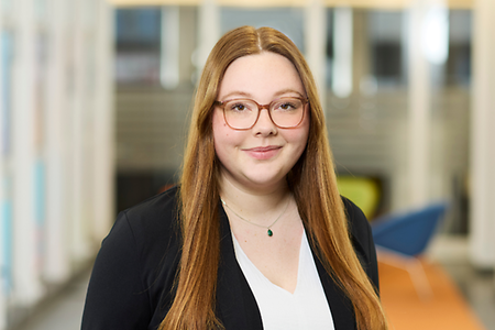 Man sieht eine junge Frau mit rotblonden Haaren und Brille.