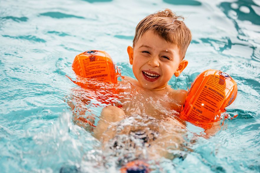 Kind mit Schwimmfl&uuml;geln im Wasser