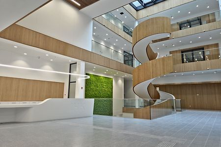 Blick ins Atrium mit Empfangstresen, Wendeltreppe und "gr&uuml;nder Wand"