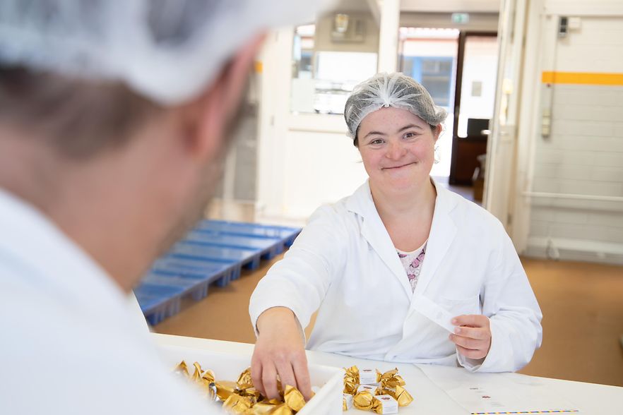 Eine Mitarbeiterin verpackt Pralinen.