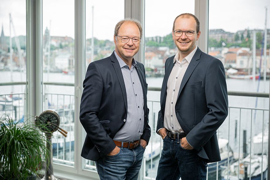 Matthias und Alexander Trost stehen nebeneinander in ihrem B&uuml;ro.