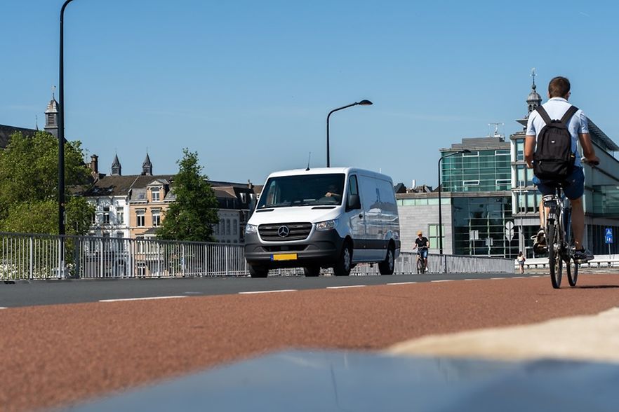 Ein Kleintransporter und Radfahrer auf einer Br&uuml;cke in Maastricht.