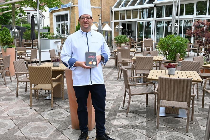 Mann mit Kochm&uuml;tze im Garten-Restaurant