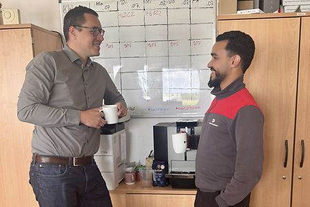 Zwei Mitarbeitende unterhalten sich bei einer Kaffeepause im B&uuml;ro.