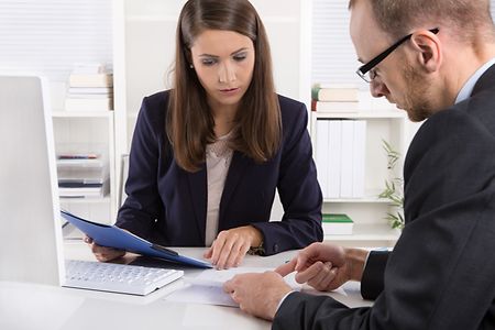 Zwei Personen in Businesskleidung sind in einem Beratungsgespr&auml;ch vertieft.