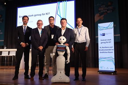 Gruppe mit humanoidem Roboter auf einer KI-Veranstaltung.