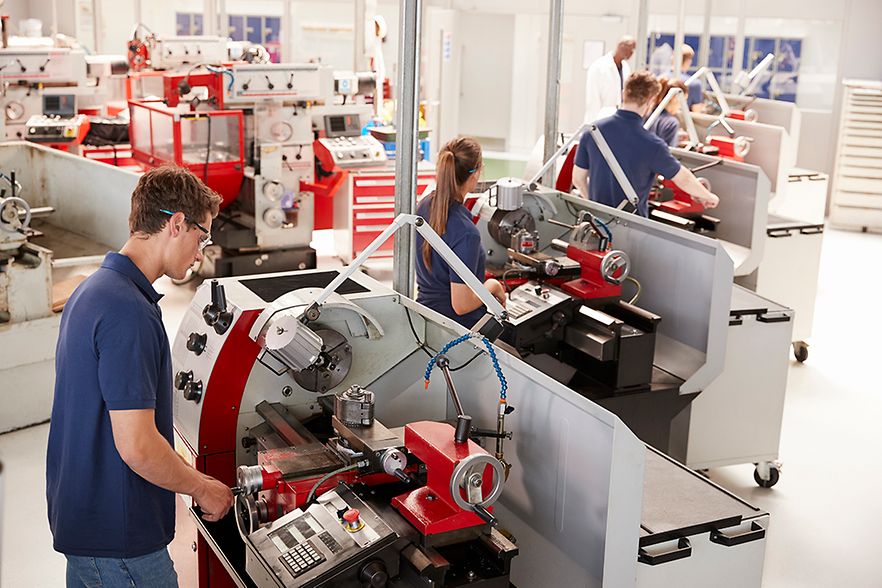 Gewerbliche Auszubildende arbeiten in einer Fabrikhalle