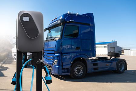 Ein Lkw an einer Lades&auml;ule auf einem Logistikgel&auml;nde.
