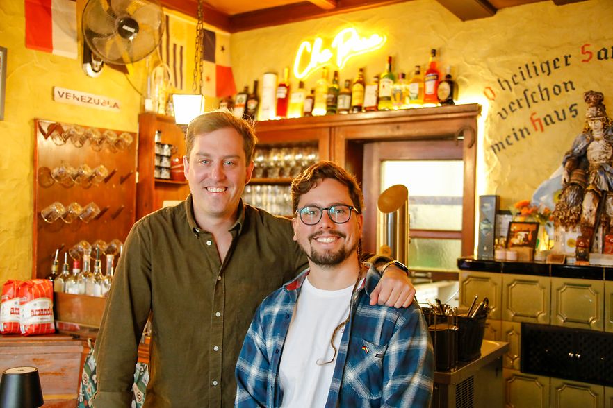 Tomas Martino und Raphael Pulgar Schwartz l&auml;chelnd in ihrer Che Pana Resto Bar. Urige Kneipe mit viel Holz an den W&auml;nden.