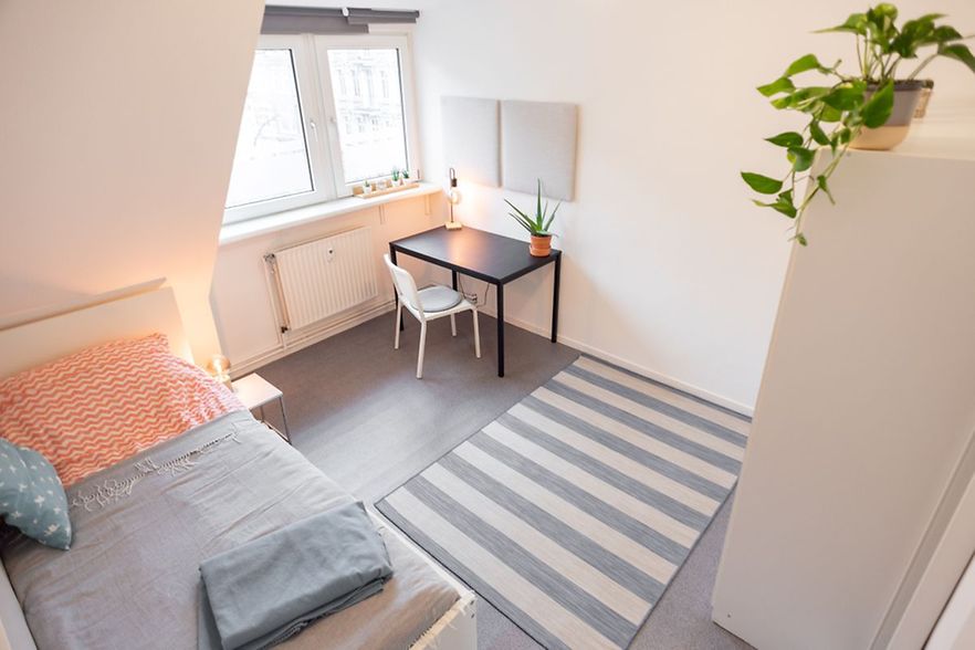 Helles, m&ouml;bliertes Apartment mit Bett, Schreibtisch und Fenster.