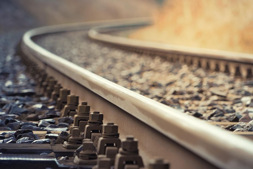 Gebogene Bahngleise mit Schotterbett und Schienenbefestigungen in Detailansicht.
