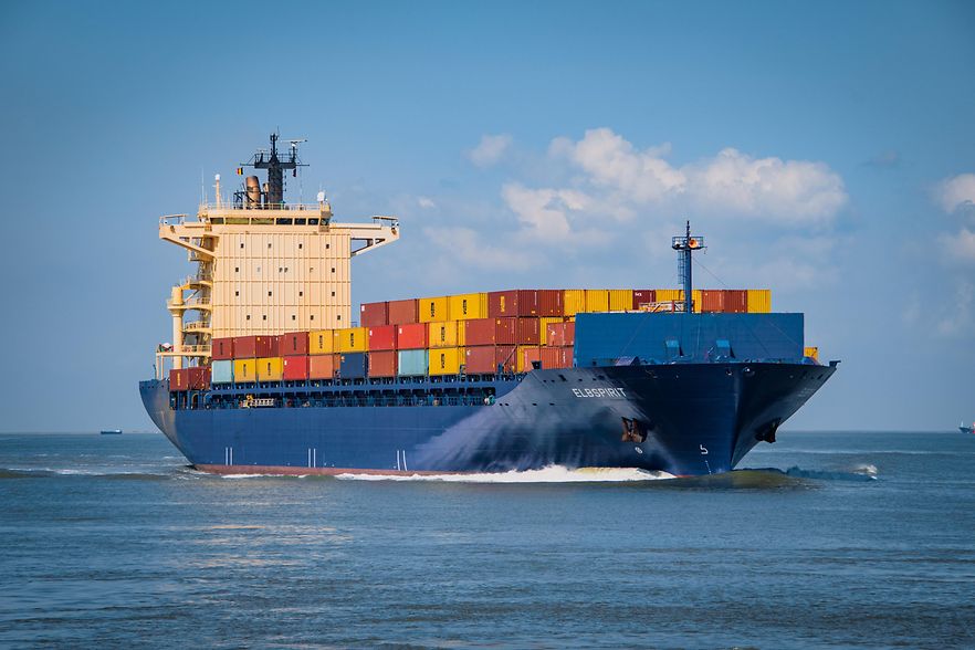 Containerschiff mit bunten Frachtcontainern auf dem Meer unterwegs.