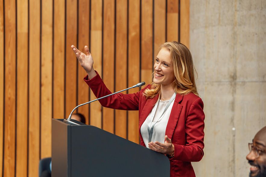 Ein Frau spricht bei einer Veranstaltung in ein Mikrofon.