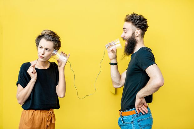 Eine Frau und ein Mann telefonieren mit einem Schnurrtelefon.