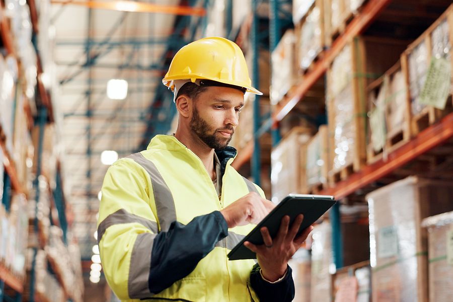 Mann mit Tablet bei Überprüfung im Werk, Versandinformationen für die Qualitätskontrolle